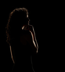 Enigmatic Elegance: Curly-Haired Woman's Silhouette On A Dark Background