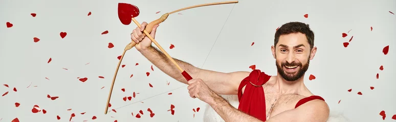 Fotobehang funny bearded cupid man archering under red confetti during st valentines party on grey, banner © LIGHTFIELD STUDIOS