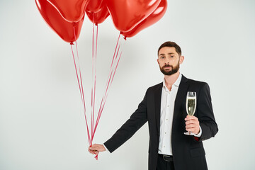 elegant man with red heart-shaped balloons and champagne glass on grey, st valentines concept - obrazy, fototapety, plakaty