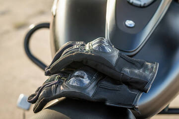 motorcyclist gloves on a motorcycle seat against a motorcycle fuel tank background close-up