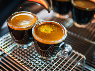 Close up of Espresso shot with coffee crema and Professional coffee machine while preparing two espressos shot glass in a coffee shop.