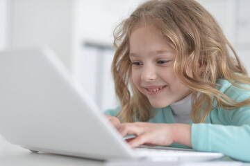 Cute and happy little girl children using laptop computer
