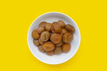 Pickled plums on yellow background.
