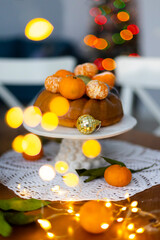 Christmas orange cake with tangerines and Christmas balls and sparkling garland on the background of Christmas tree