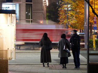 冬の夜の東京駅前の交差点で信号待ちの人々の姿