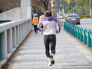 秋の皇居外苑の道で走るランナーたちの姿