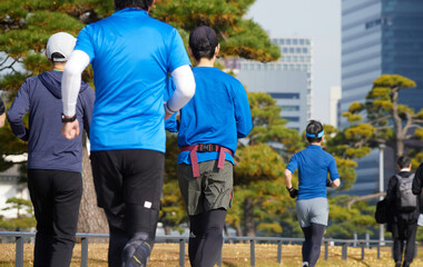 秋の皇居外苑の周辺で走るランナー達と東京都の都心の高層ビルの風景