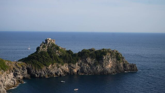 Cinematic view from mountain on Stone Tower on rocky Coast with blue sea. Torre Capo di Conca - historical landmark on Conca dei Marini, Amalfi Coast, Italy, Europe. Shooting in slow motion.