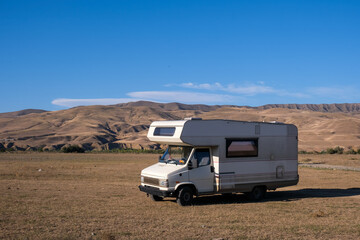 motorhome in a field among desert mountains