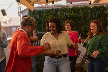 group of friends dancing on the terrace while toasting. the focus is on a young curvy african american woman