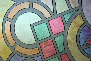 Unusual hand-drawn color film with a mosaic pattern glued to the glass of the balcony of an apartment. Graphic squares, circles, circles, and angles.