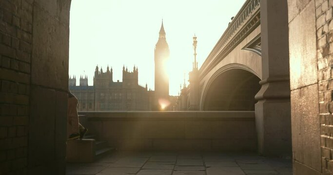 Cinematic shot of mother with boy and girl, leaving the observation deck with epic view of Big Ben in bright sunlight.