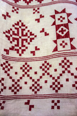 Close-up detail of antique red cross stitch embroidery on white canvas