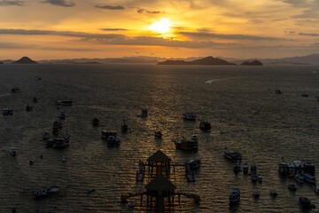 Tour Boats anchored at port of Labuan Bajo during sunset.