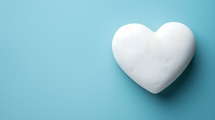 Top View of a White Stone Heart on a light blue Background. Romantic Template with Copy Space