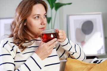 Young woman drinking her winter tea at home