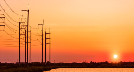 Silhouette row of electric poles near shrimp ponds in the vast aquaculture livestock farm area...
