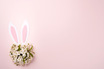 Happy Easter. Bunny rabbit ears made of pink paper and round bouquet of springs fresh cherry or apple blossoms on pink background. Easter greeting card with copy space. Happy Easter concept. Mock up