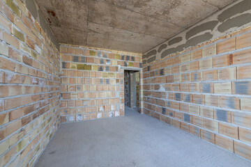 Unfinished room interior of building under construction. Brick walls. New home.