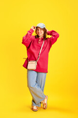 Full length portrait of happy cheerful student, tourist dressed oversized clothes against vivid yellow background. Concept of fashion and style, traveling, vacation, culture, fun and joy.