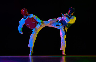 Competitive strong young men, taekwondo, karate athletes in motion, fighting, training against...