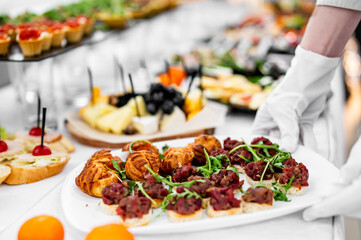 woman hands of a waiter prepare food for a buffet table in a restaurant