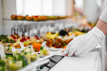 woman hands of a waiter prepare food for a buffet table in a restaurant - obrazy, fototapety, plakaty