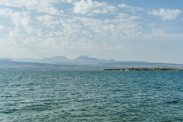 view of sevan huge blue lake shore with mountain peaks far ahead