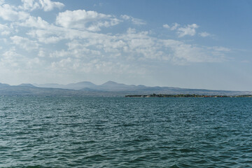 view of sevan huge blue lake shore with mountain peaks far ahead windy with waves