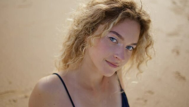 Serene model posing sand beach looking camera with carefree smile close up. 