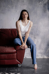 Portrait of an attractive girl with a charming smile. A girl of oriental appearance sits on the floor in a stylish apartment. Lifestyle