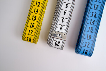 Multi-colored measuring tapes on a light background. Tool for measuring length and volume. Tape for...