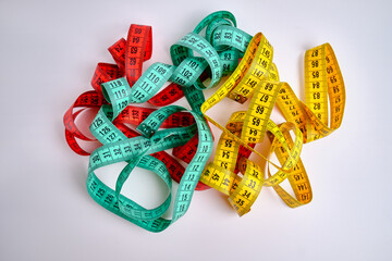Multi-colored measuring tapes on a light background. Tool for measuring length and volume. Tape for...