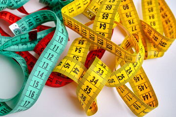 Multi-colored measuring tapes on a light background. Tool for measuring length and volume. Tape for measuring in sewing production or the volume of the human body
