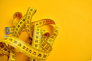 Yellow measuring tape on a yellow background. Tool for measuring length and volume. Tape for...