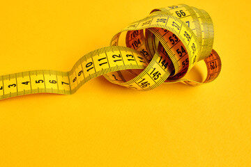 Yellow measuring tape on a yellow background. Tool for measuring length and volume. Tape for...