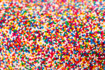 Macro shot of a cake with white icing encrusted in rainbow sprinkles