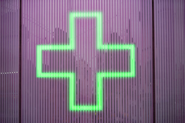 Green neon light with shape of cross at pharmacy at Swiss City of Zürich on a rainy winter day. Photo taken December 22nd, 2023, Zurich, Switzerland.