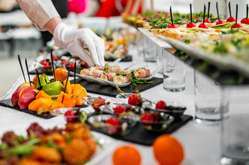 woman hands of a waiter prepare food for a buffet table in a restaurant