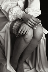 Morning of the bride before the wedding. A beautiful young woman with a veil and a beautiful hairstyle in a white robe near her wedding dress on a mannequin. Professional makeup. Last preparations.