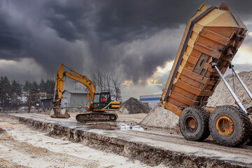 View a excavator and dumper truck on a brownfield site in the construction industry. Construction equipment.