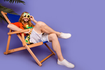 Full length photo of cool man dressed shirt lay on deckchair drink cocktail touch funny sunglass...