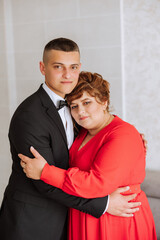 mother helps her adult son prepare for the wedding ceremony. An emotional and touching moment at a wedding. A mother hugs her son