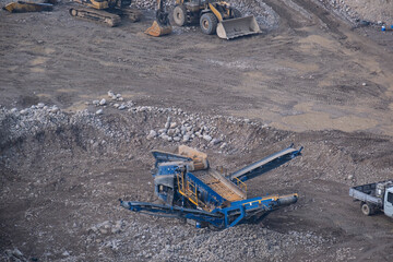 A large, deep crushed stone quarry with heavy equipment at the bottom