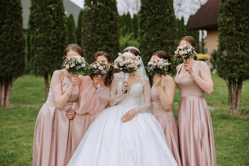 Group portrait of the bride and bridesmaids. Bride in a wedding dress and bridesmaids in pink or...