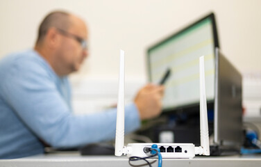 Wi-Fi router installed on a desktop in the office. In the background you can see a man working at a...