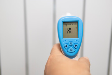 Measuring the temperature of a heating radiator using an electronic thermometer. A man measures the...