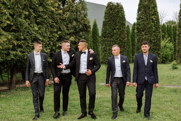 Cheerful, young, energetic witnesses of the groom next to the groom. Friends congratulate the groom. Groom and his funny friends having fun on the wedding day of the newlyweds.