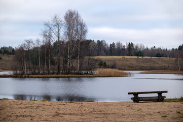 Autumn landscape on a lake with empty bench, horizontal picture