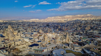 Göreme's panoramic vista: From a peak, the town sprawls below, a blend of ancient architecture and modern life nestled amidst Cappadocia's timeless landscape.